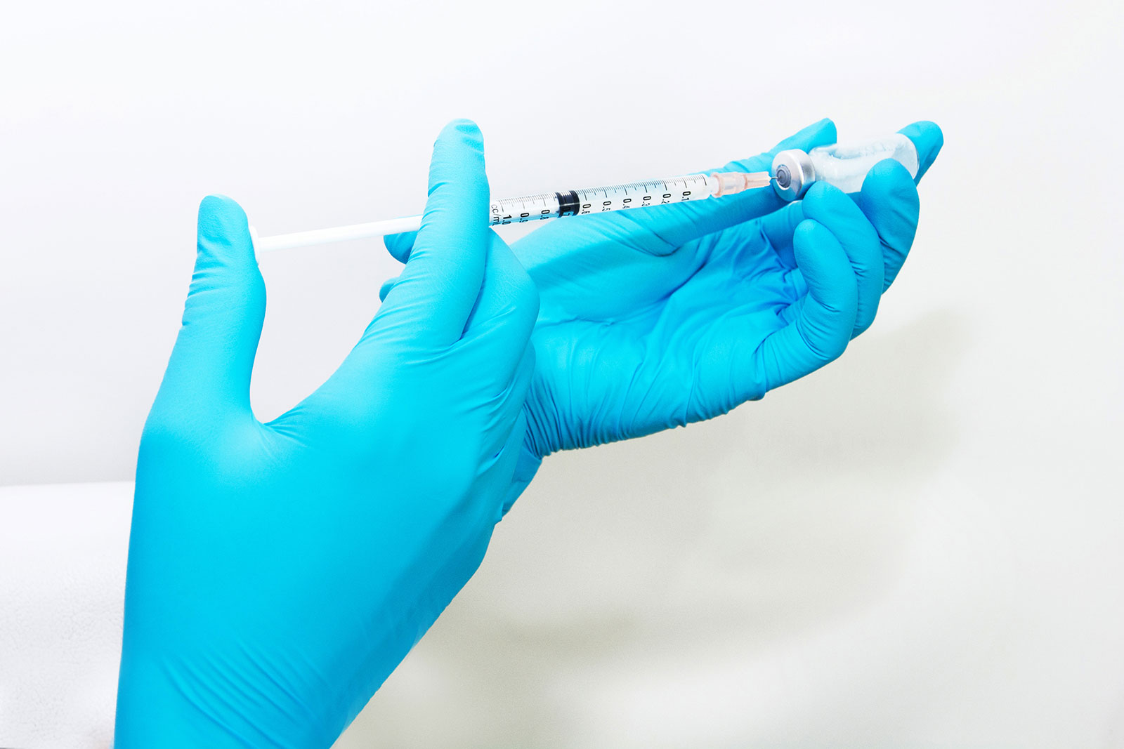 Gloved hand holding syringe and vial